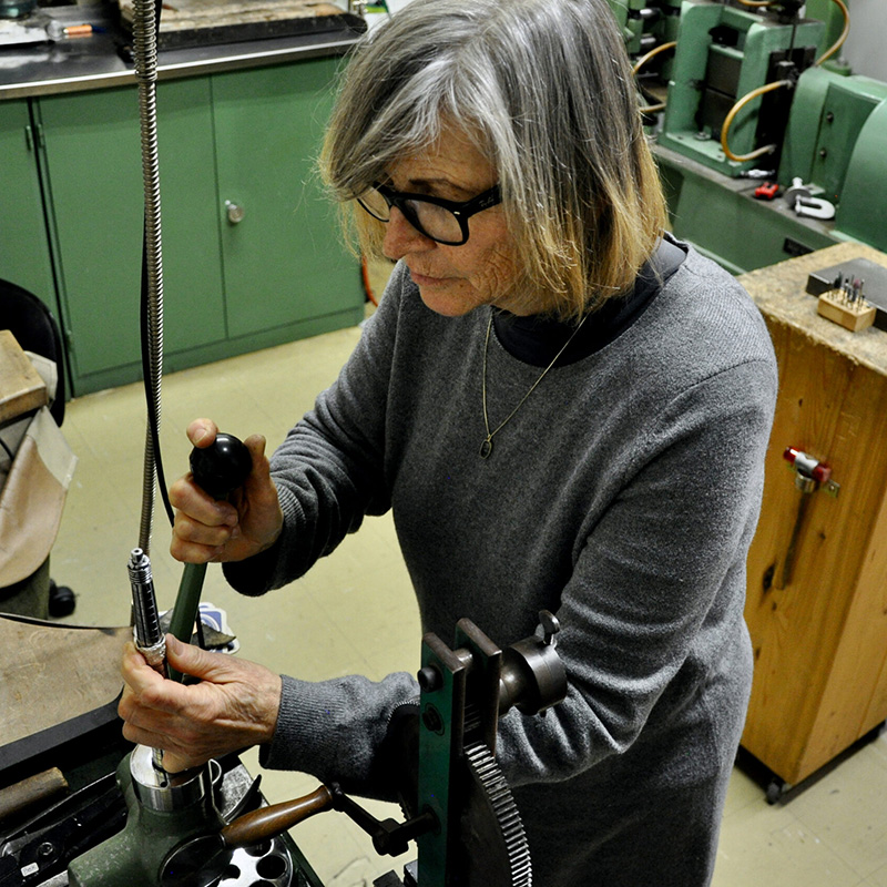 Ein Bild von Helga Beck, die Schmuck in einer Werkstätte herstellt.